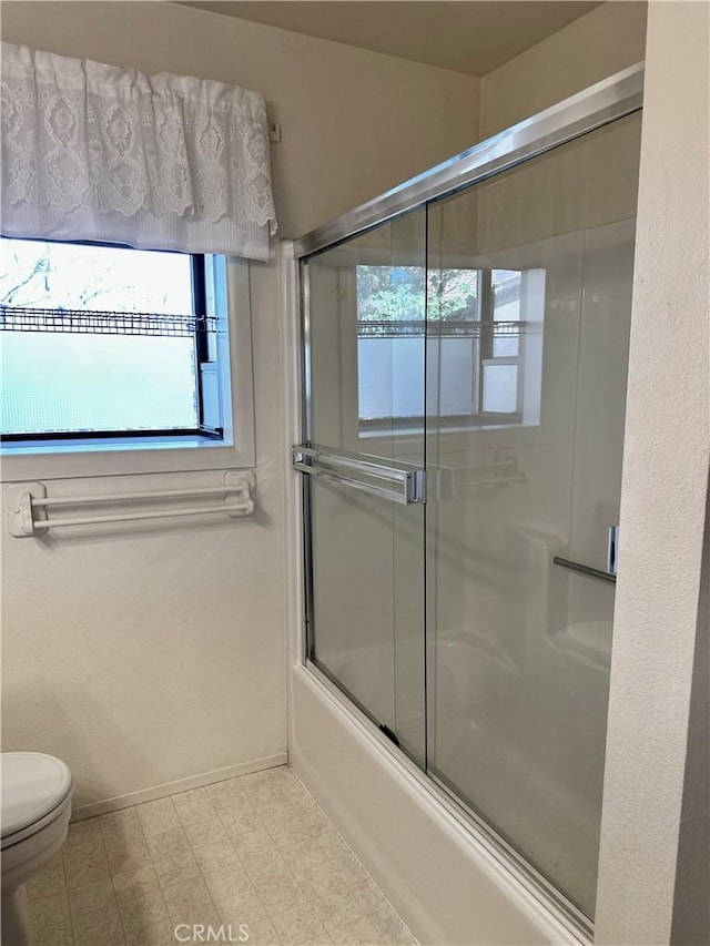 bathroom featuring baseboards, shower / bath combination with glass door, toilet, and tile patterned floors