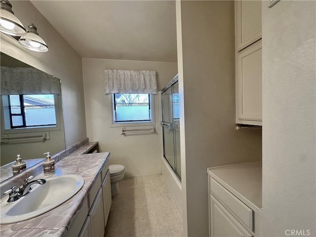 bathroom featuring baseboards, shower / bath combination with glass door, vanity, and toilet