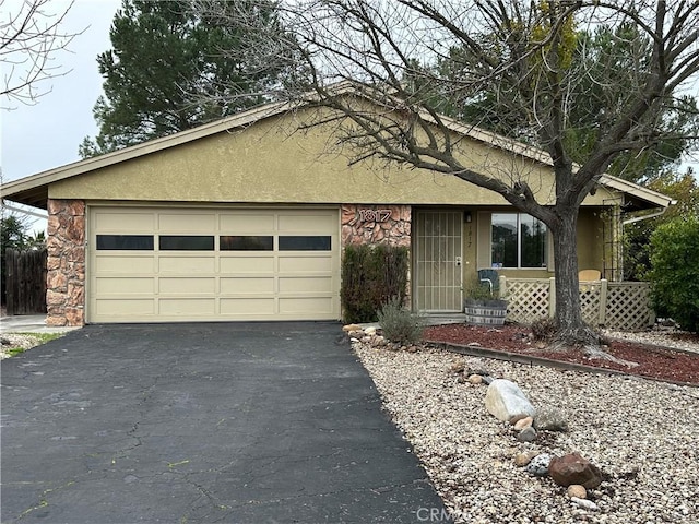 view of front of house with stone siding, aphalt driveway, an attached garage, and stucco siding