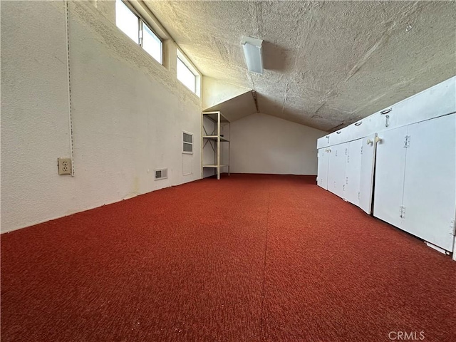 additional living space with lofted ceiling, visible vents, carpet flooring, and a textured ceiling