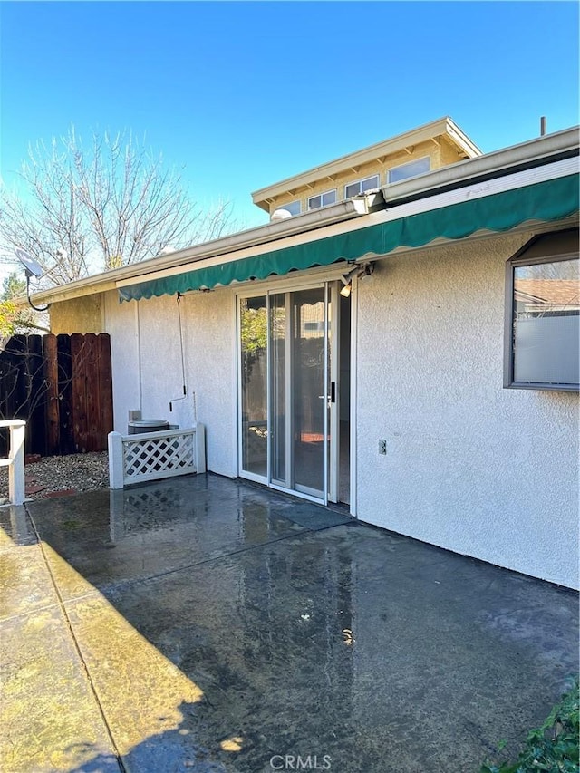 view of exterior entry with a patio area and stucco siding