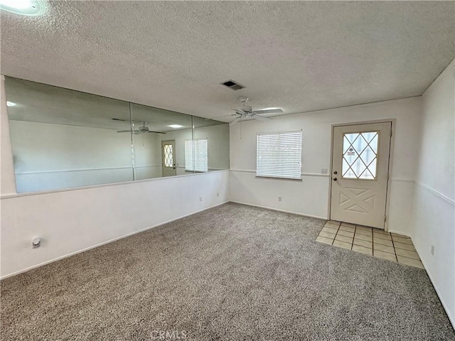 carpeted foyer with a textured ceiling, visible vents, and a ceiling fan