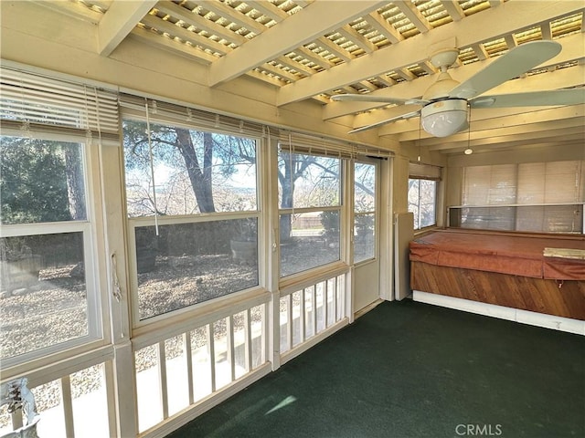 unfurnished sunroom featuring a ceiling fan and beamed ceiling