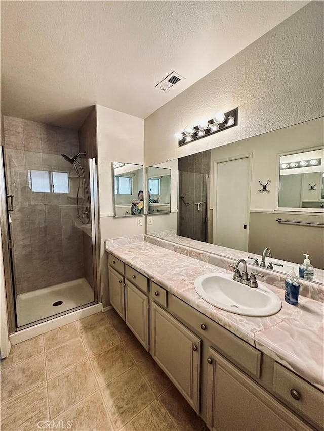 bathroom featuring a stall shower, visible vents, tile patterned flooring, a textured ceiling, and vanity