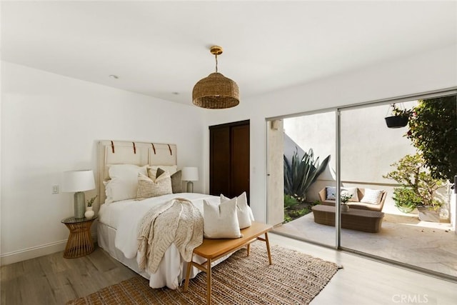 bedroom with access to outside, wood finished floors, and baseboards