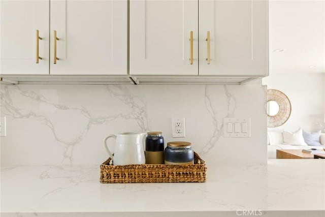 room details with backsplash, white cabinets, and light stone countertops