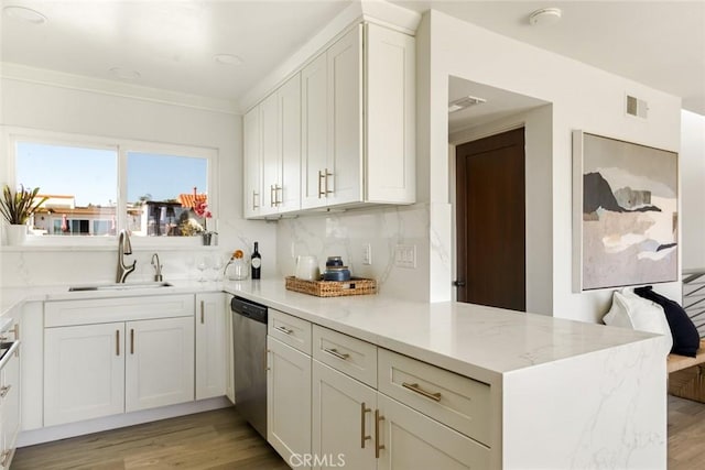 kitchen featuring visible vents, dishwasher, a peninsula, light stone countertops, and a sink