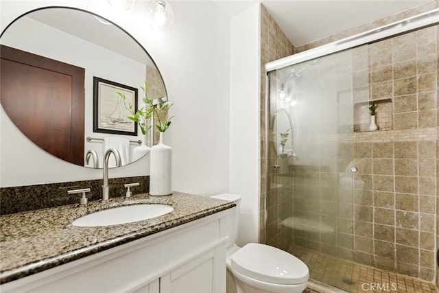 full bath featuring toilet, a stall shower, and vanity