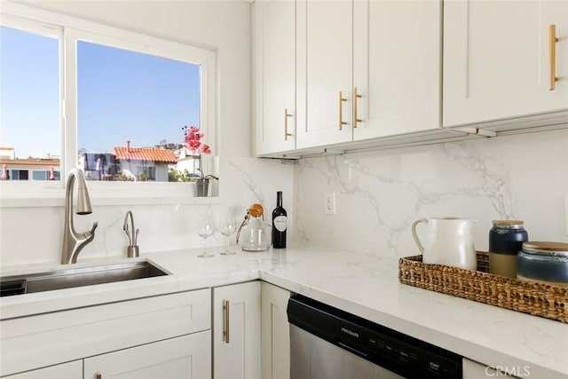 kitchen featuring light stone counters, a sink, white cabinetry, decorative backsplash, and dishwasher