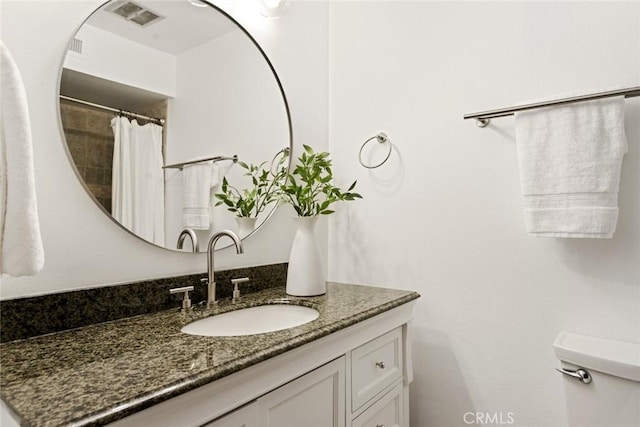 bathroom featuring toilet, visible vents, and vanity