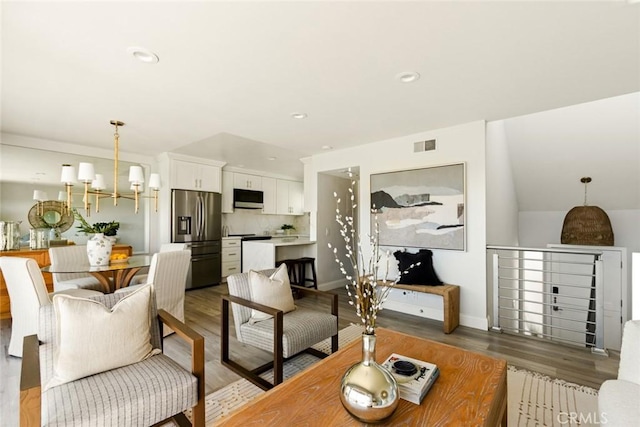 living room with a chandelier, recessed lighting, visible vents, and wood finished floors