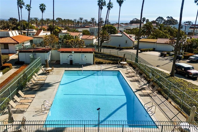 community pool featuring a residential view, fence, and a patio