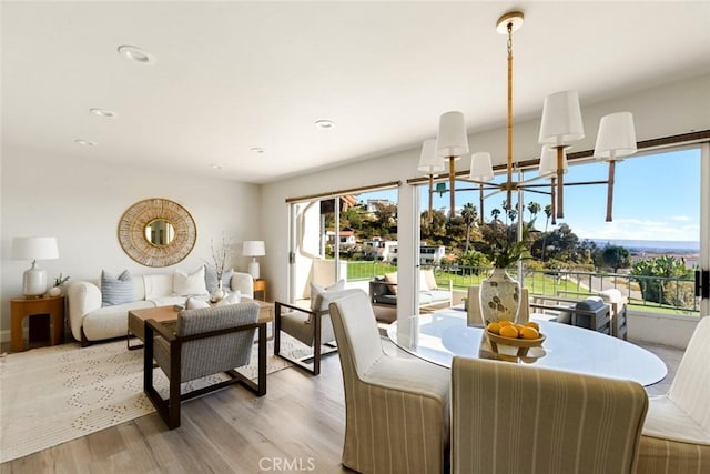 dining room with recessed lighting, light wood-style flooring, and a notable chandelier