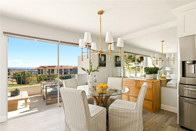 dining area featuring baseboards, light wood-style flooring, and a notable chandelier