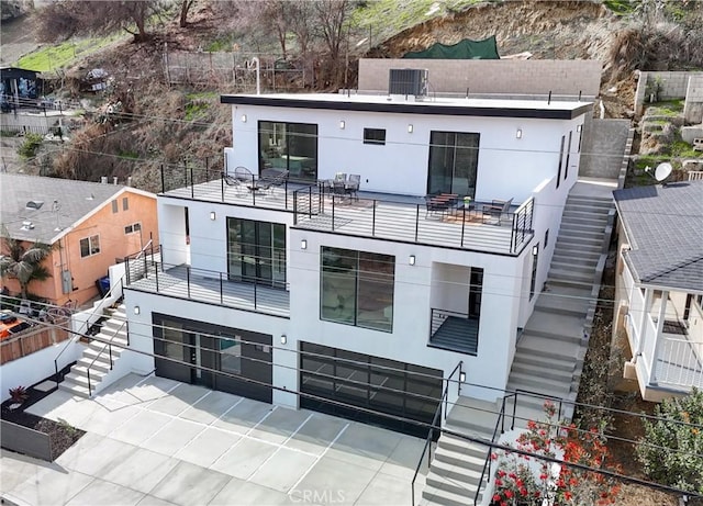 rear view of house featuring fence, stairway, a balcony, and stucco siding