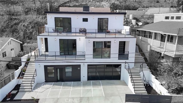 exterior space with stairway, an attached garage, and stucco siding