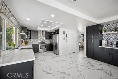 kitchen with appliances with stainless steel finishes, light countertops, a sink, and open shelves