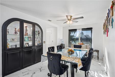 dining room with a ceiling fan and marble finish floor