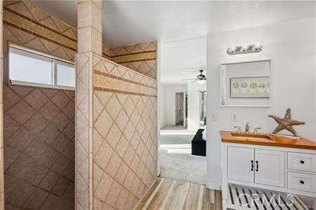 full bath featuring a ceiling fan, a walk in shower, wood finished floors, and vanity