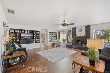 living room with a brick fireplace, ceiling fan, visible vents, and concrete flooring