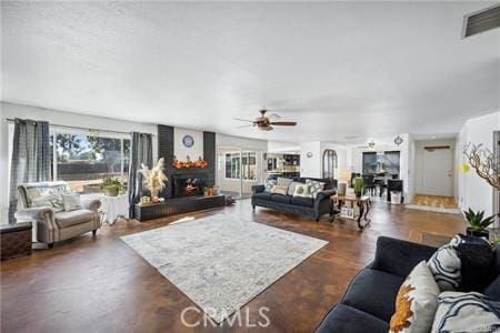 living area with a large fireplace, visible vents, and a ceiling fan