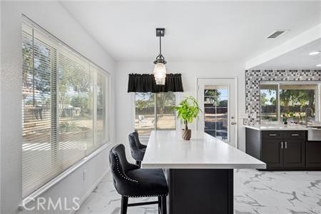 dining area with a healthy amount of sunlight, marble finish floor, and visible vents