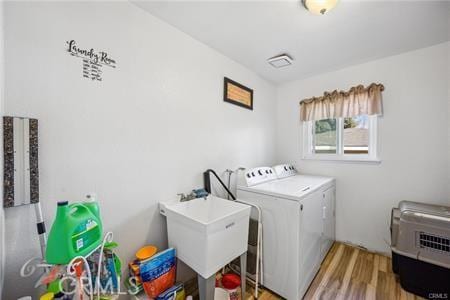 washroom featuring a sink, laundry area, washer and clothes dryer, and light wood finished floors