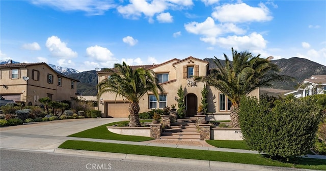 mediterranean / spanish house featuring a garage, driveway, a mountain view, and stucco siding