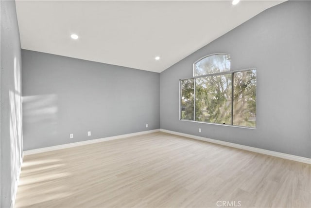 spare room featuring lofted ceiling, recessed lighting, baseboards, and light wood-style floors