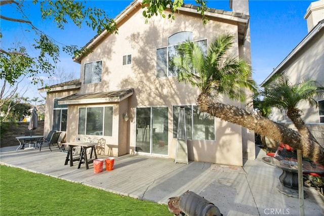 back of house with a deck, a patio, and stucco siding