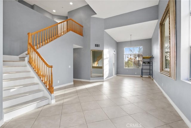 foyer featuring light tile patterned floors, stairway, visible vents, and baseboards