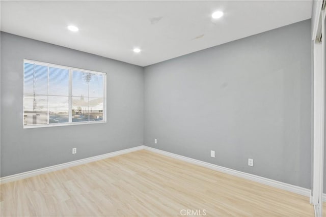 spare room featuring recessed lighting, light wood-style flooring, and baseboards