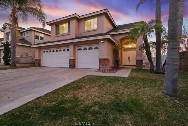 traditional-style home with a garage, a lawn, driveway, and stucco siding