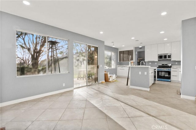 kitchen with a breakfast bar area, white cabinetry, light countertops, appliances with stainless steel finishes, and a center island with sink