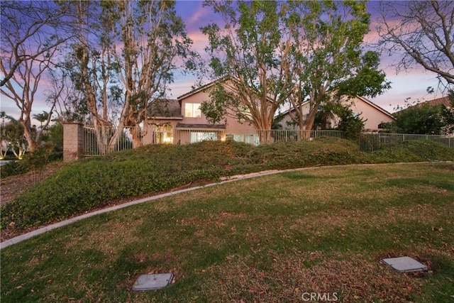 view of front of home featuring fence, a lawn, and stucco siding