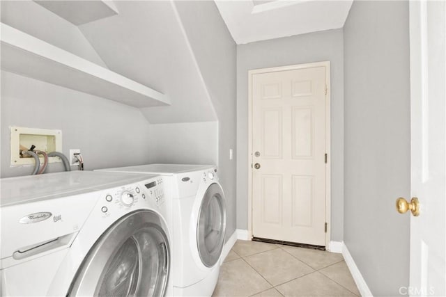 clothes washing area featuring laundry area, washing machine and dryer, light tile patterned floors, and baseboards