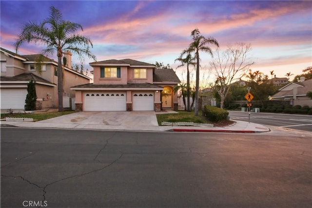 view of front facade featuring a garage, stone siding, concrete driveway, and stucco siding