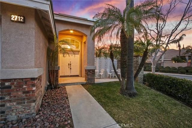 entrance to property with a lawn and stucco siding