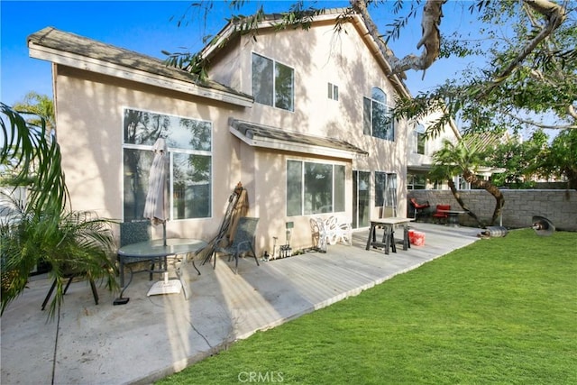 rear view of house with fence, a lawn, a patio, and stucco siding