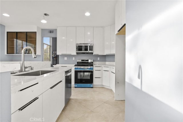 kitchen featuring stainless steel appliances, light countertops, white cabinetry, a sink, and modern cabinets