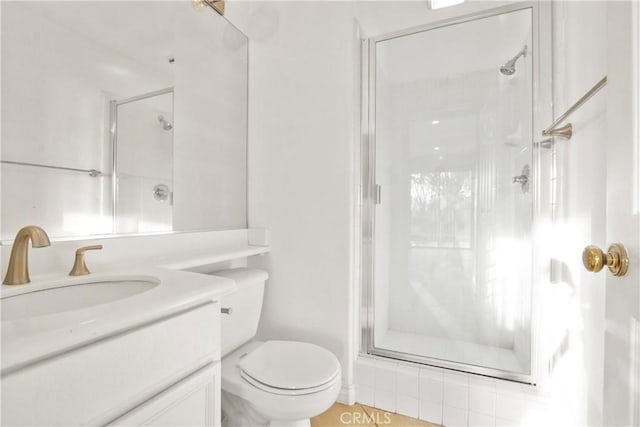 bathroom featuring toilet, a shower stall, and vanity