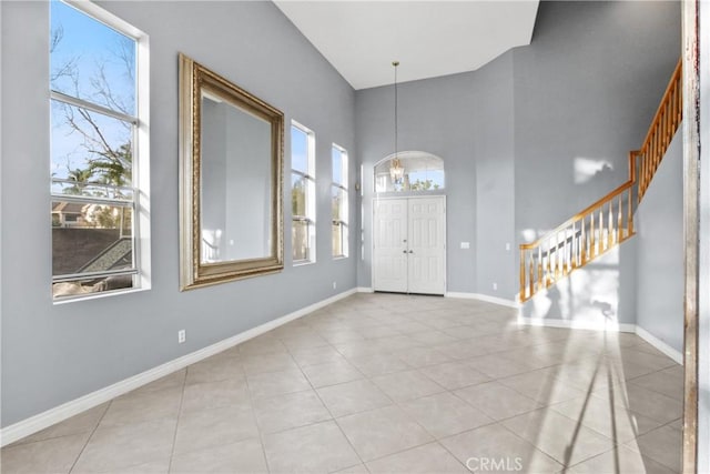 entrance foyer featuring light tile patterned floors, stairway, baseboards, and an inviting chandelier