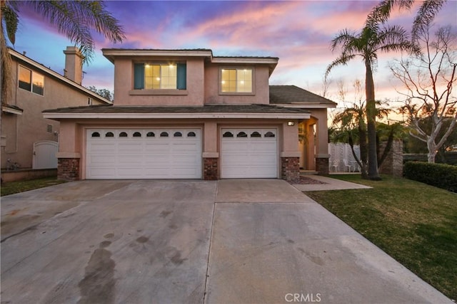 traditional-style home featuring a garage, concrete driveway, stone siding, and stucco siding