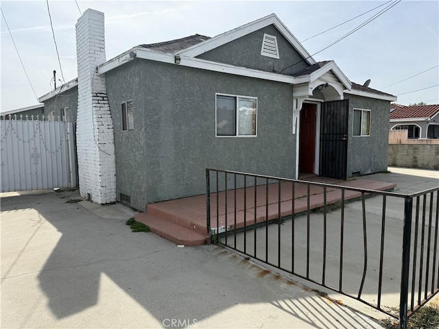 rear view of property featuring fence and stucco siding