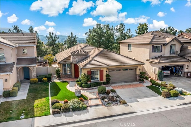 view of front of house featuring a tile roof, stucco siding, fence, driveway, and a front lawn