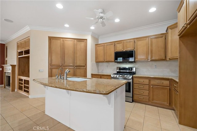 kitchen with light stone counters, stainless steel gas range, a kitchen island with sink, and brown cabinets