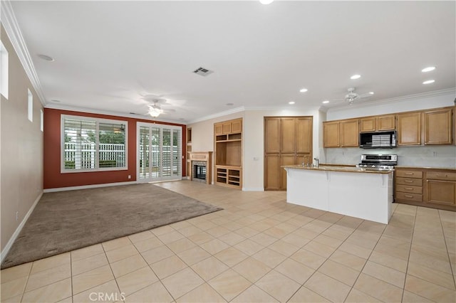 kitchen with black microwave, open floor plan, brown cabinetry, stainless steel range, and an island with sink