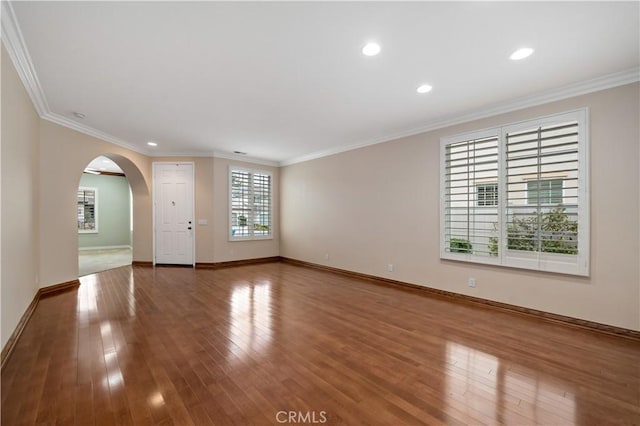 empty room with crown molding and wood finished floors