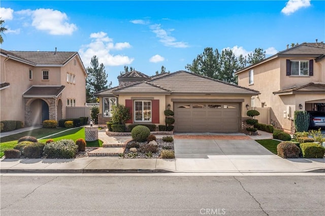 view of front facade featuring a garage, driveway, a tiled roof, and stucco siding