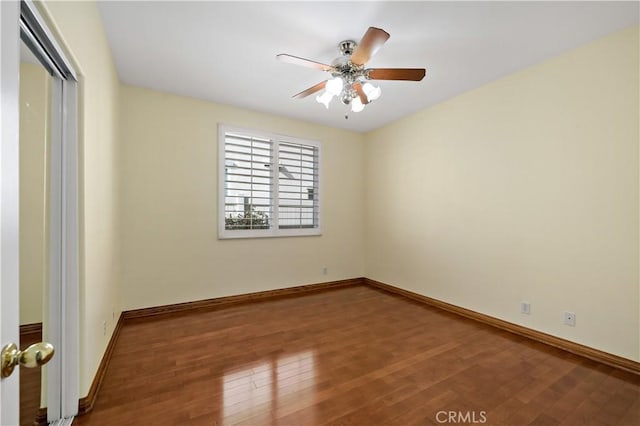 empty room featuring a ceiling fan, baseboards, and wood finished floors